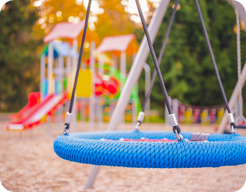 Columpio en un parque infantil con otras estructuras de juegos.